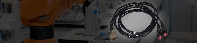 Coiled cable assembly with circular connectors beside an industrial robot arm on a production line